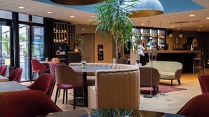 En moderne restaurant med højt til loftet, store hængelamper og et centralt siddeområde med et rundt bord.