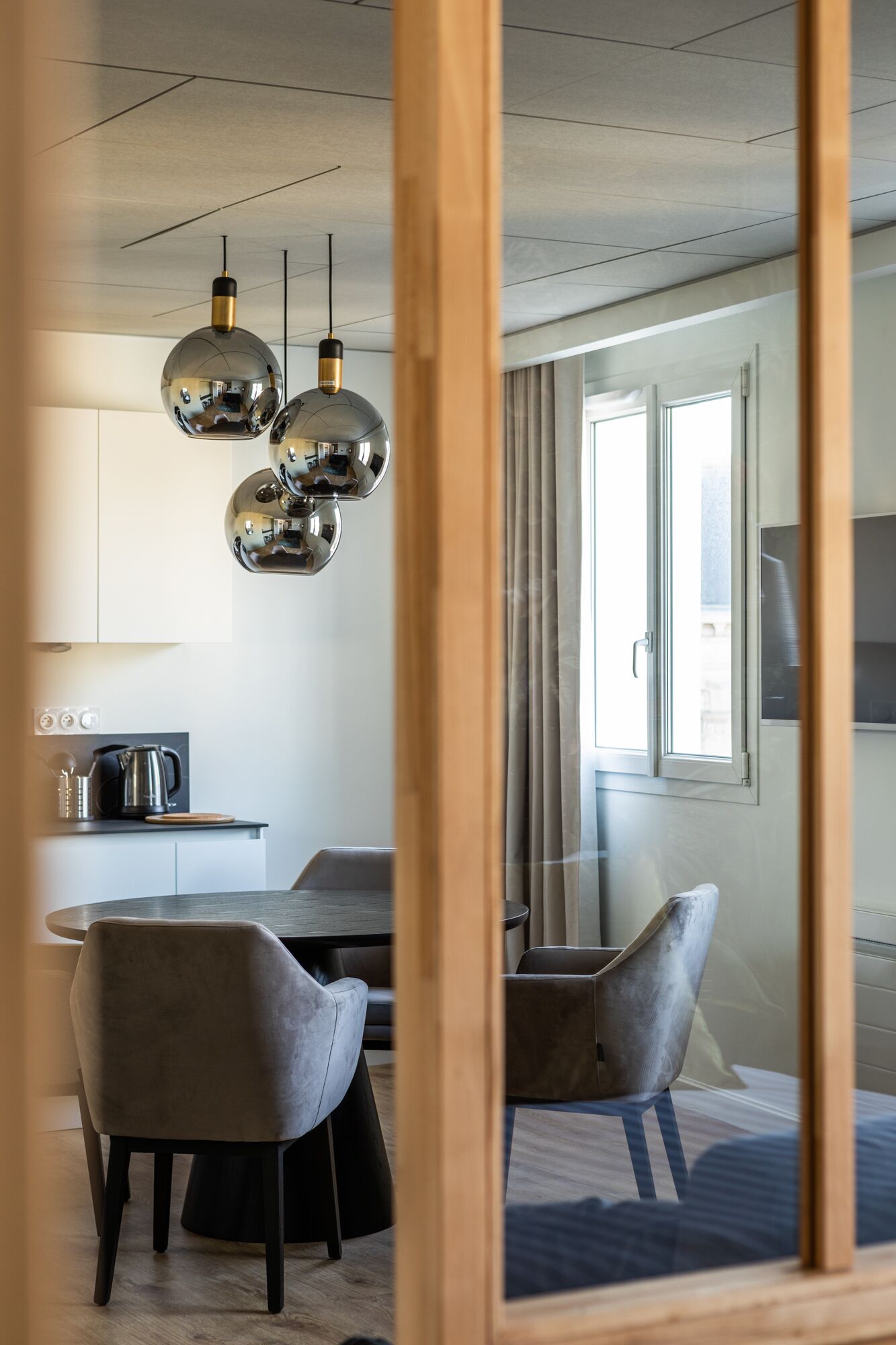 Moderni keittiö, jossa on ruokailutila. Tilaan kuuluu pyöreä pöytä, kaksi tuolia ja riippuvalaisimet.