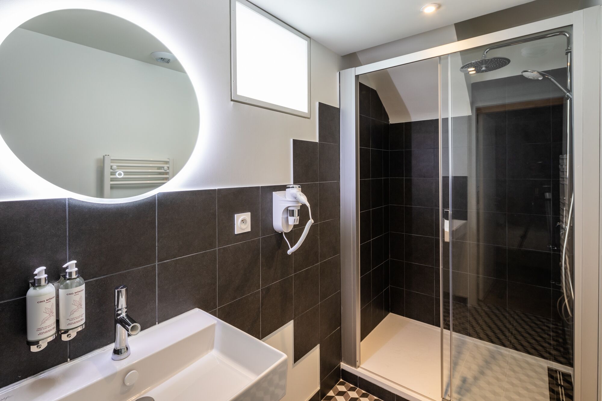 A modern bathroom with a large mirror, a sink, and a shower area.