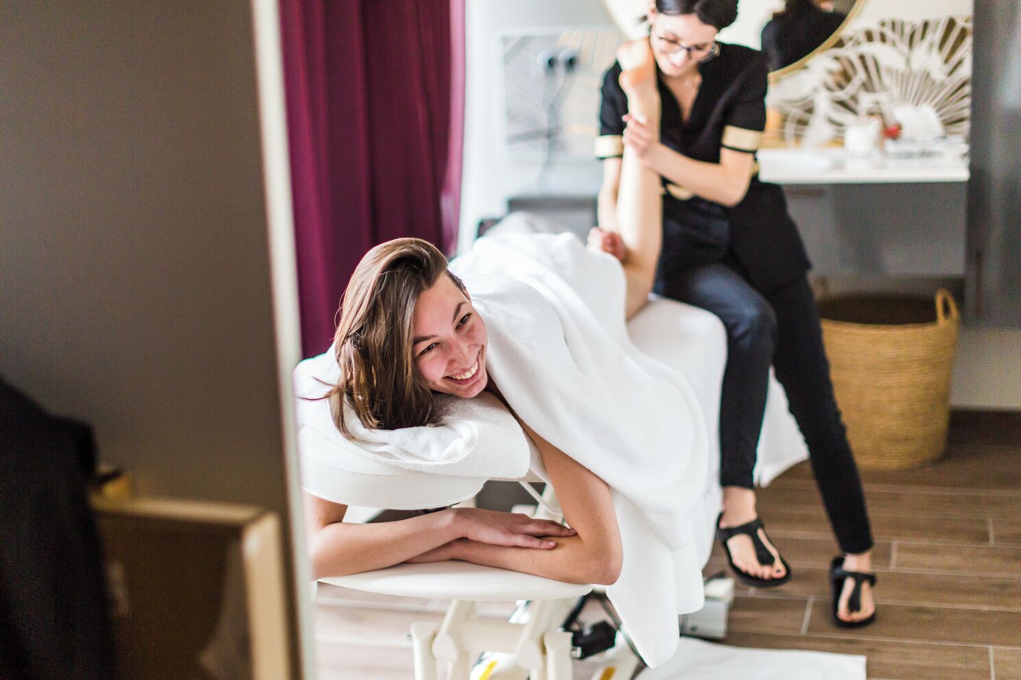 A room with a massage table, a massage therapist, and a client receiving a massage.