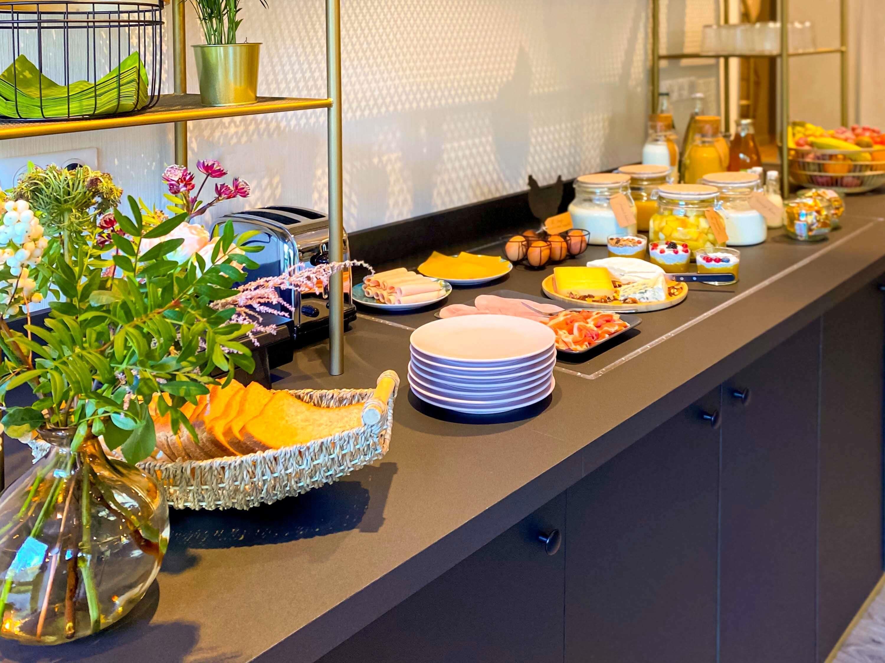 Un buffet proposant une variété de plats, des assiettes et une composition florale décorative.