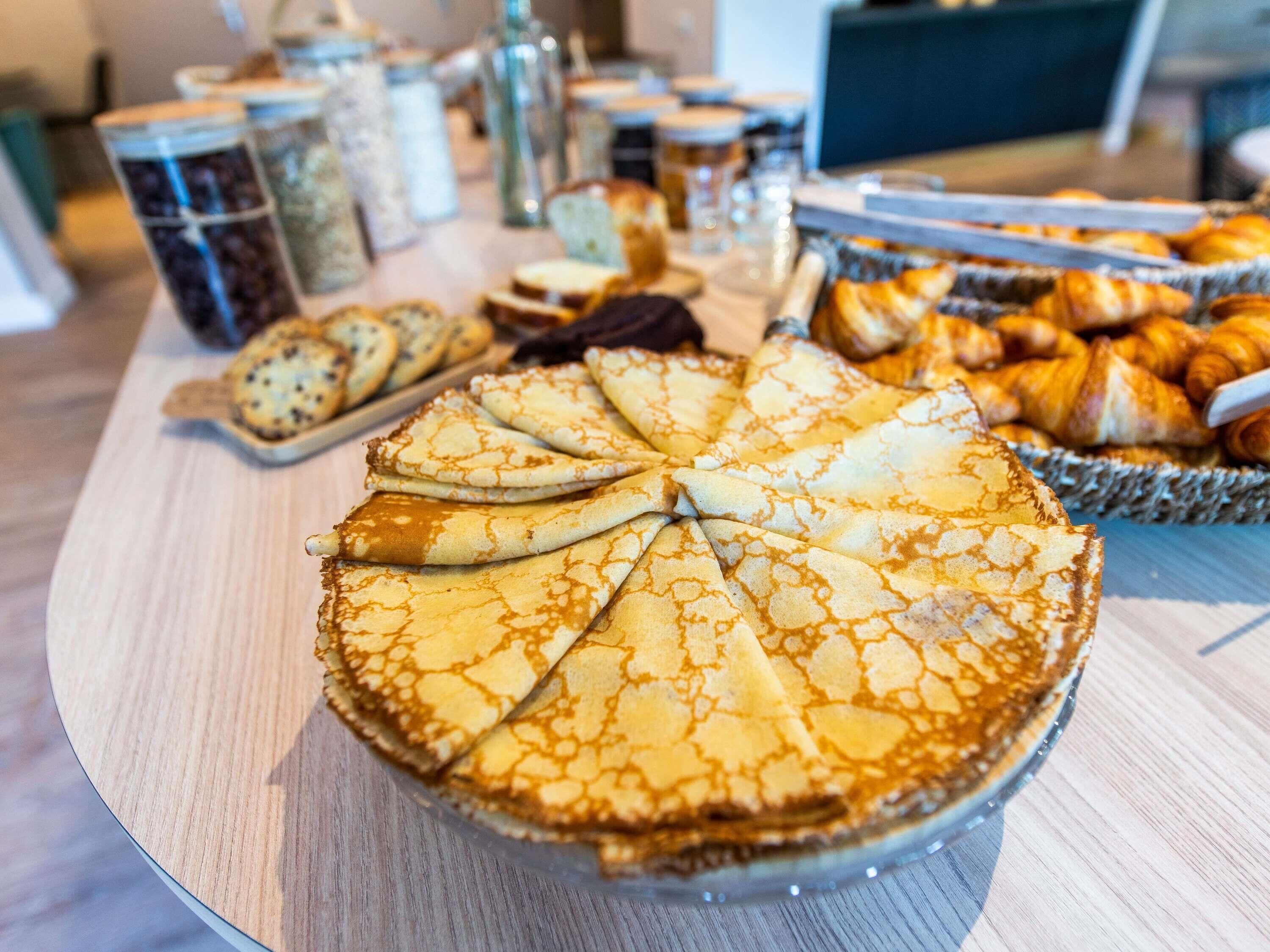 A buffet table with various baked goods, including a large pie and pastries.