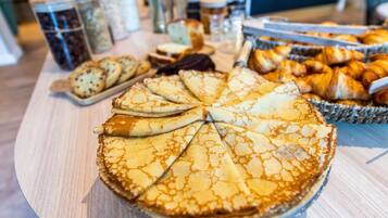 A buffet table with various baked goods, including a large pie and pastries.