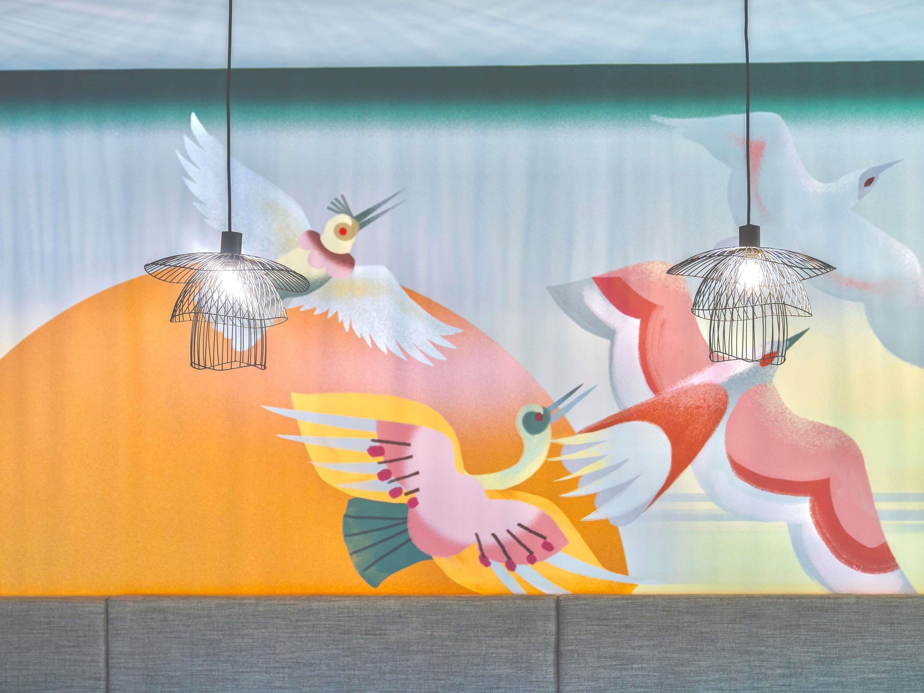 A wall with a colorful mural of birds and hanging light fixtures.