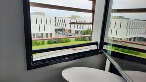 A modern room with a balcony, a small table, and a chair. - ibis Styles Rennes Cesson (Cesson-Sevigne)