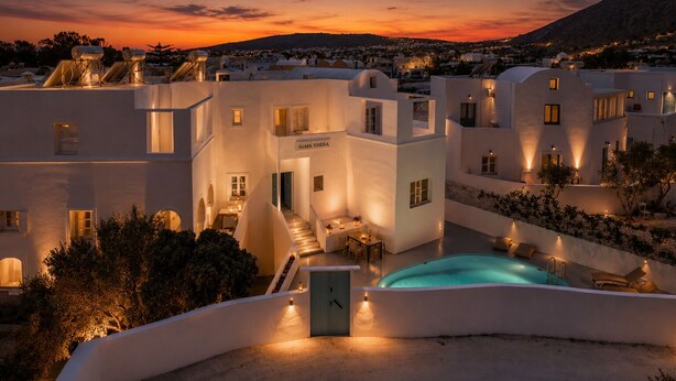 Un hotel moderno con piscina, mobiliario exterior y vistas a la puesta de sol.