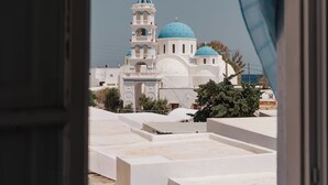 Vista a través de una ventana que muestra un edificio con una estructura de cúpula azul, posiblemente una iglesia o mezquita, y fachada blanca.