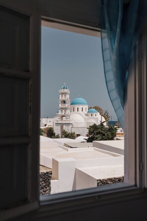 A view through a window of a building with a blue-domed structure, possibly a church or mosque, and a white exterior.