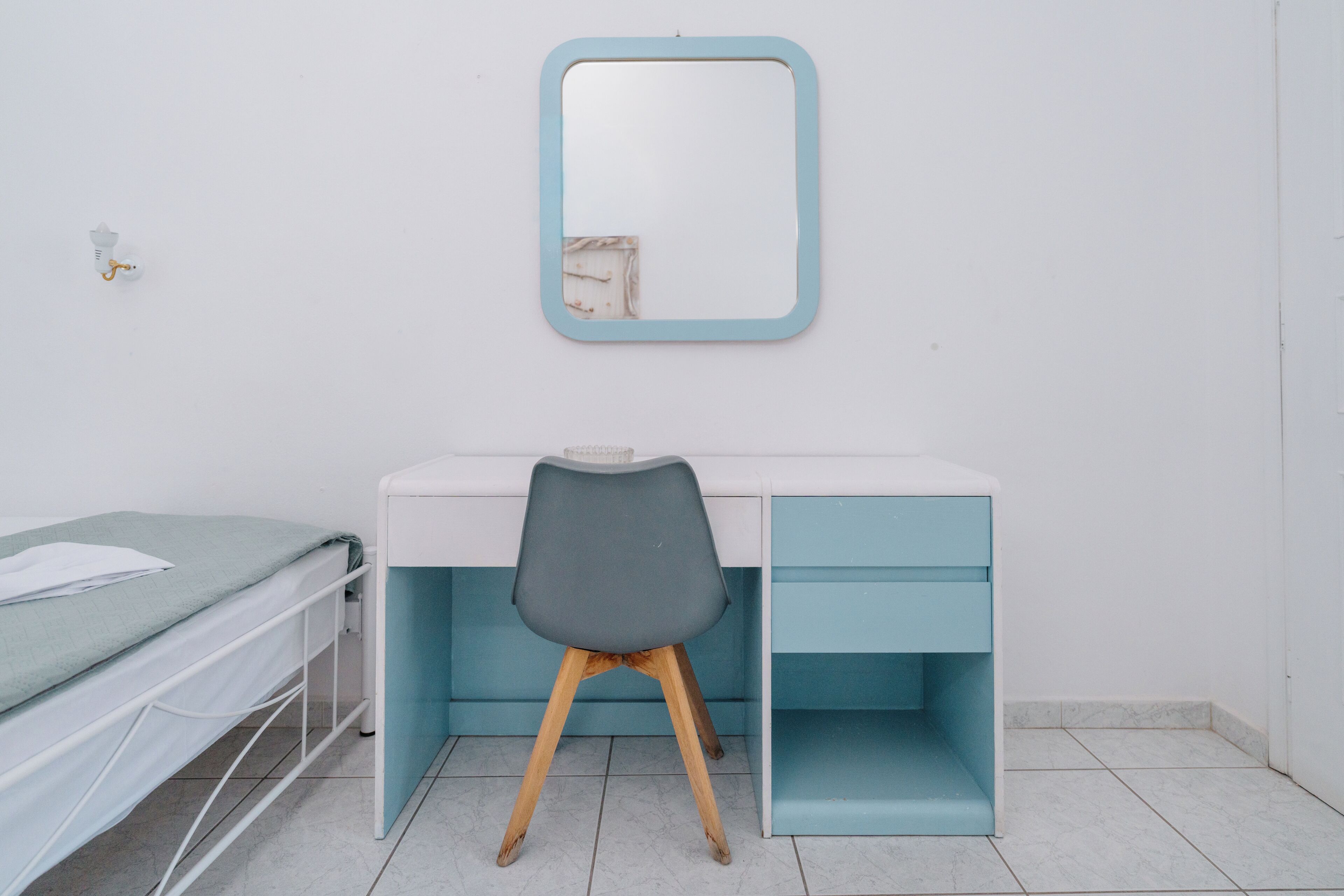 Un dormitorio con cama, escritorio, silla, espejo y armario.