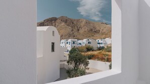 Un edificio blanco con balcón que da a un pueblo de casas blancas y una montaña.