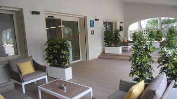 Un espacio al aire libre con mobiliario de mimbre, una mesa de centro y plantas en macetas.