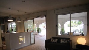 Een hotel lobby met een receptiebalie, een bank en grote ramen met uitzicht op de omgeving.