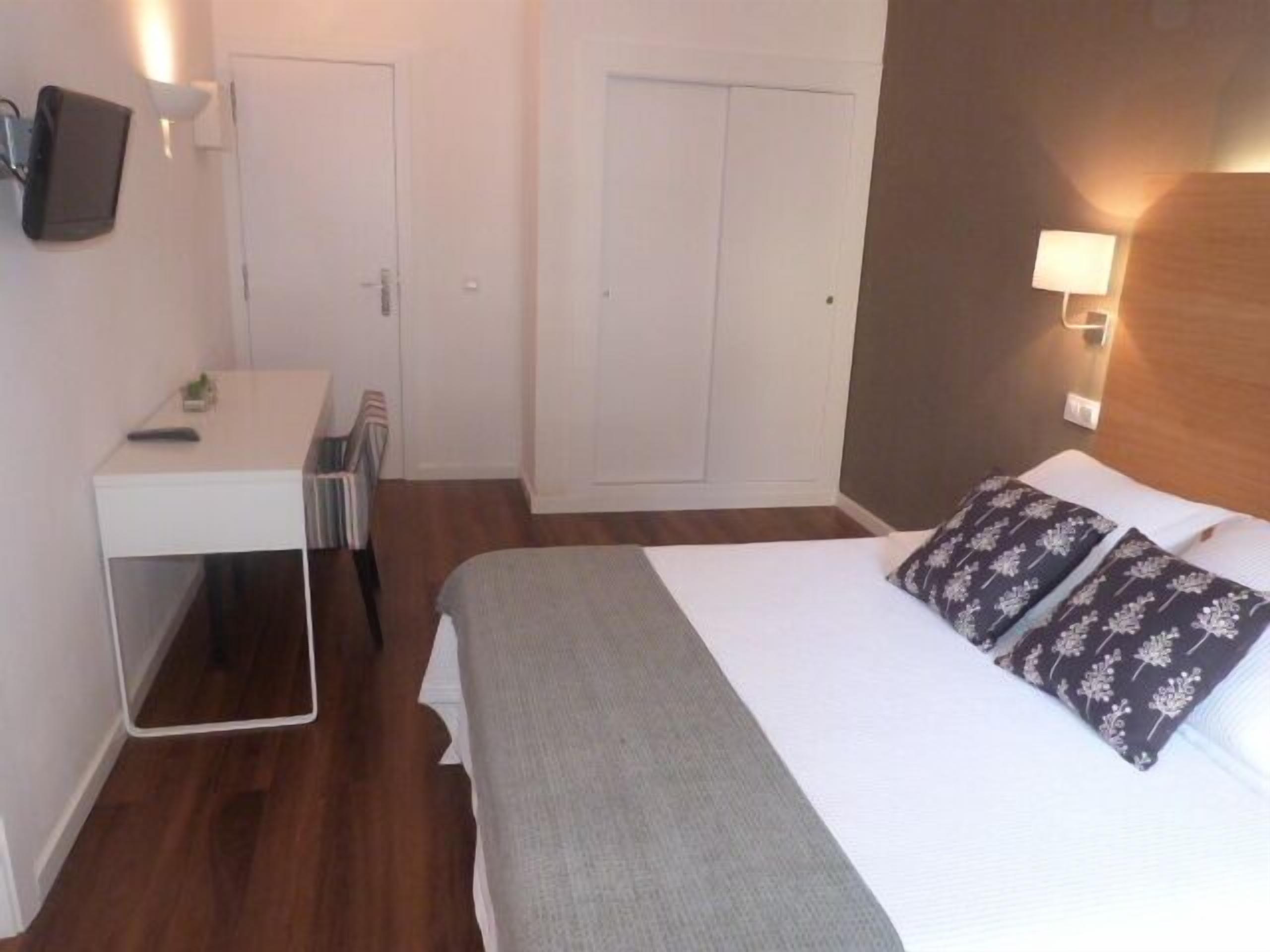 Una habitación de hotel con cama, escritorio y armario.