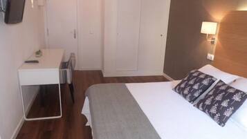 Una habitación de hotel con cama, escritorio y armario.