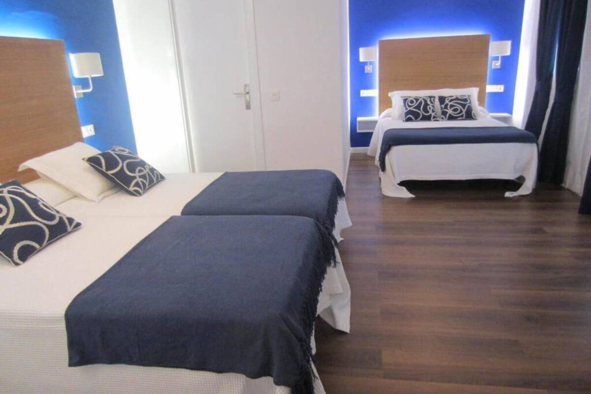 A hotel room with two beds, wooden flooring, and blue accent walls.