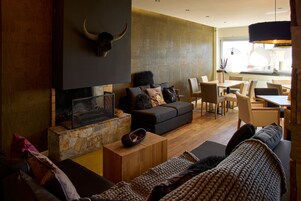 Uma sala de estar moderna com lareira, parede de destaque em pedra e área de jantar com iluminação natural.