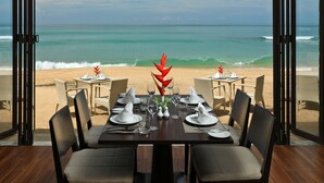 Une table à manger dressée pour six personnes, avec vue sur la plage et l’océan.