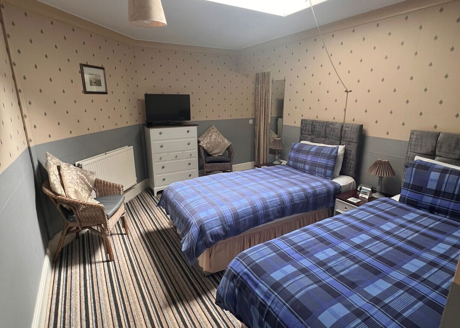 A bedroom with two beds, a dresser, a television, and a chair.