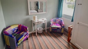 A child's room with a striped floor, a white dresser, a colorful chair, and a mirror on the wall. - Rosedene Guesthouse (Pembroke)