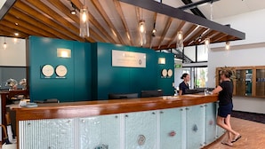 Un comptoir d’accueil aux couleurs turquoise, des horloges indiquant les différents fuseaux horaires et un panneau accueillant les clients à la résidence du gouverneur.