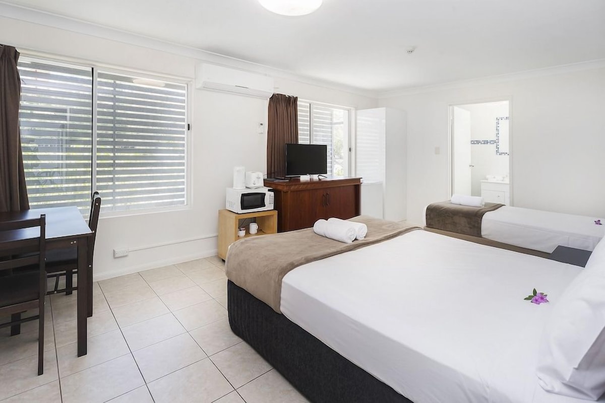 A hotel room with a bed, a desk, a television, and a microwave.