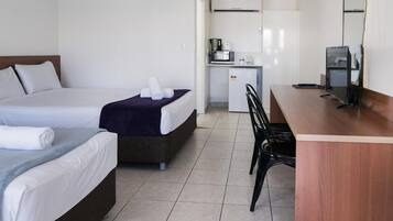 A hotel room with two beds, a kitchenette, a desk, and a chair.