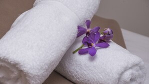 A neatly folded white towel with a purple orchid placed on top. - Sunshine Beach Resort (Miami)