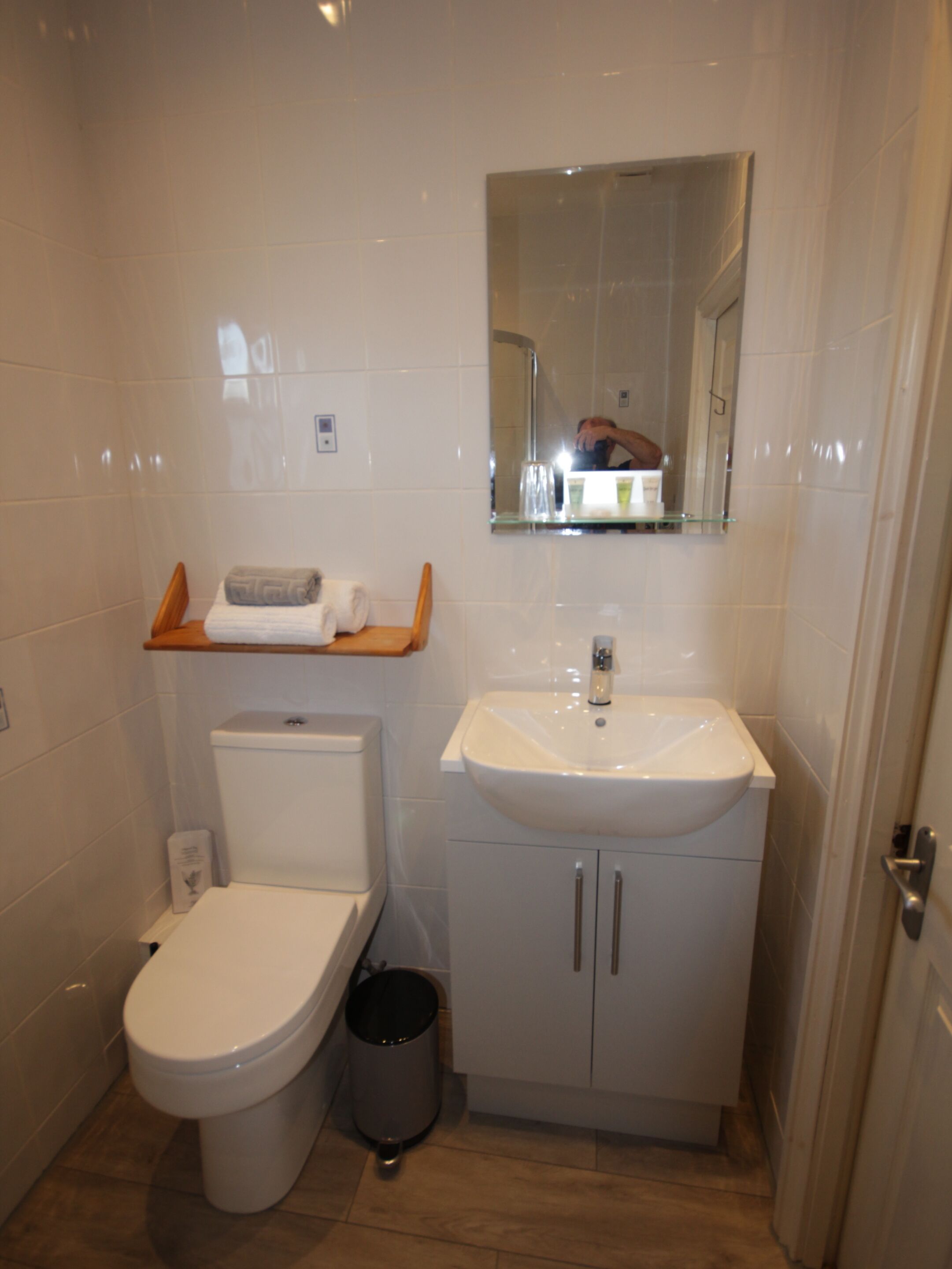 Een kleine badkamer met toilet, wastafel en spiegel.