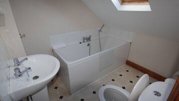 Un baño con tragaluz, bañera, lavabo e inodoro.