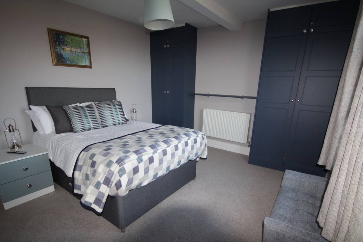 A bedroom with a bed, bedside table, lamp, and a painting on the wall.