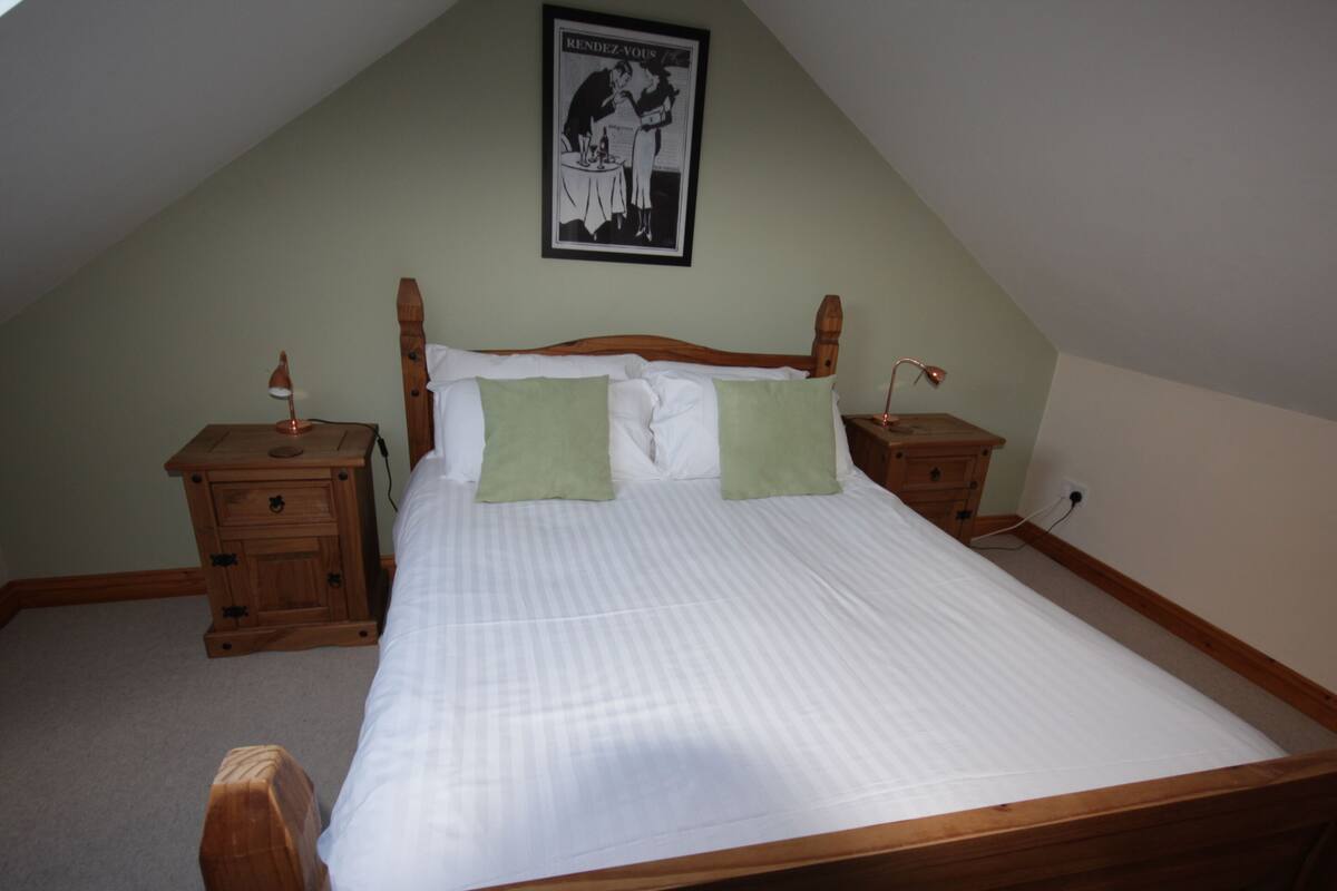 A bedroom with a wooden bed, two nightstands, a lamp on each, and a poster on the wall.