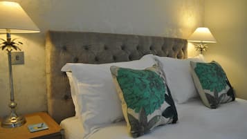 A neatly made bed with a tufted headboard, two bedside lamps, and floral-patterned pillows.