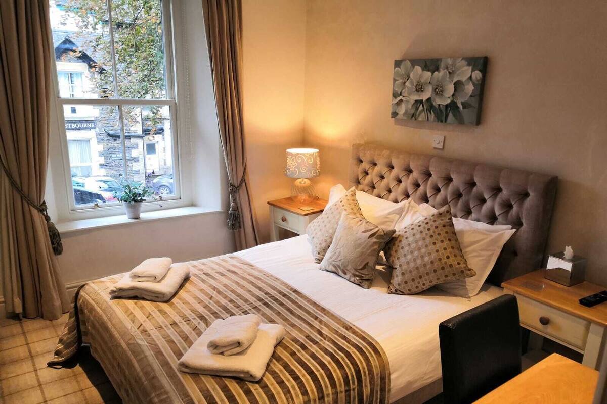 A neatly made bed with a striped bedspread, a tufted headboard, and a bedside lamp.