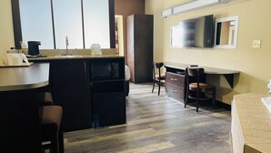 A modern kitchen with a central island, a microwave, and a coffee machine. There is a dining area with a chair and a small table. A flat-screen TV is mounted on the wall above the counter. - Microtel Inn & Suites by Wyndham Harrisonburg (Harrisonburg)