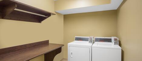 A laundry room with a built-in washer and dryer, a wooden bench, and a ceiling light.