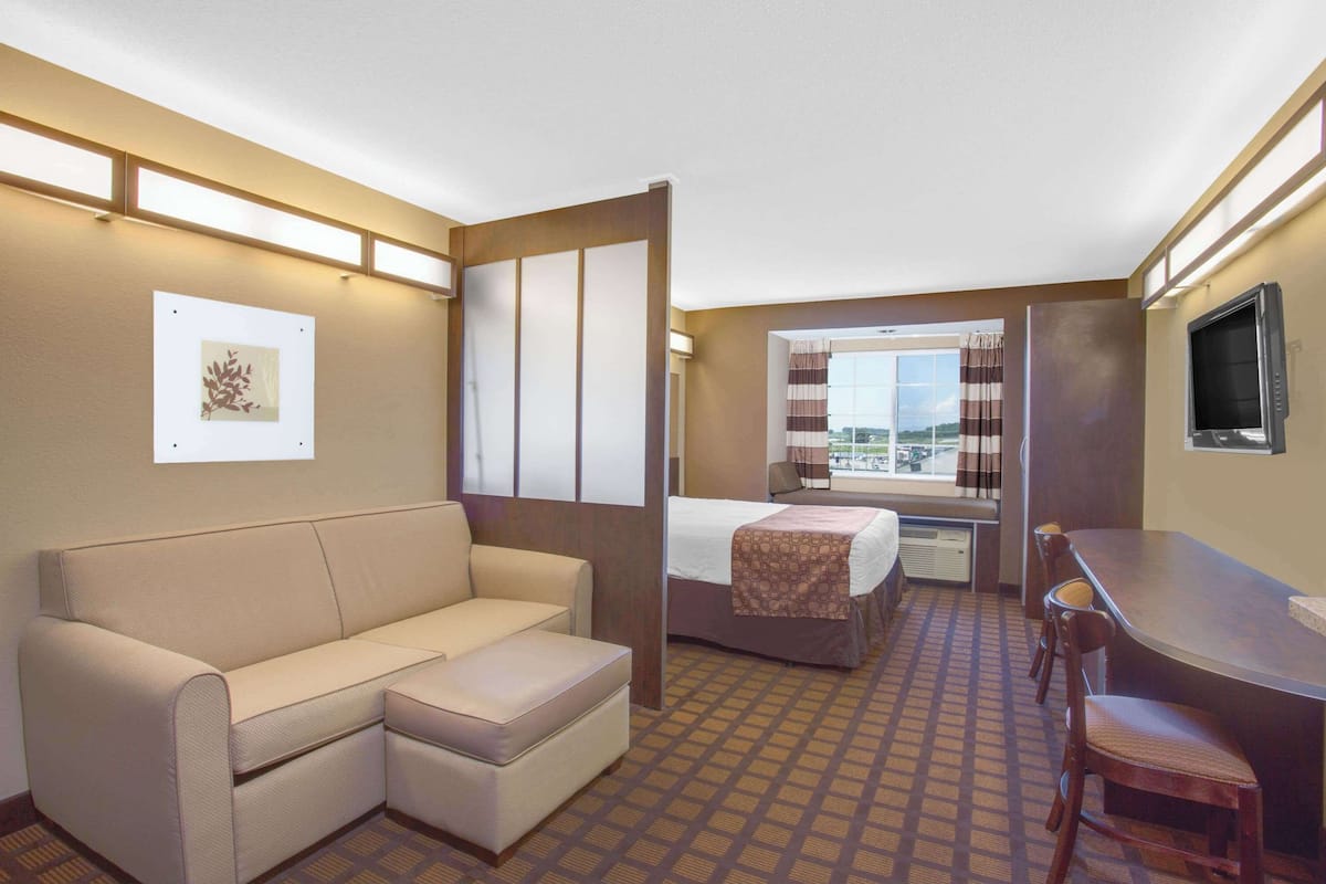 A hotel room with a sofa, a bed, a desk, and a TV.