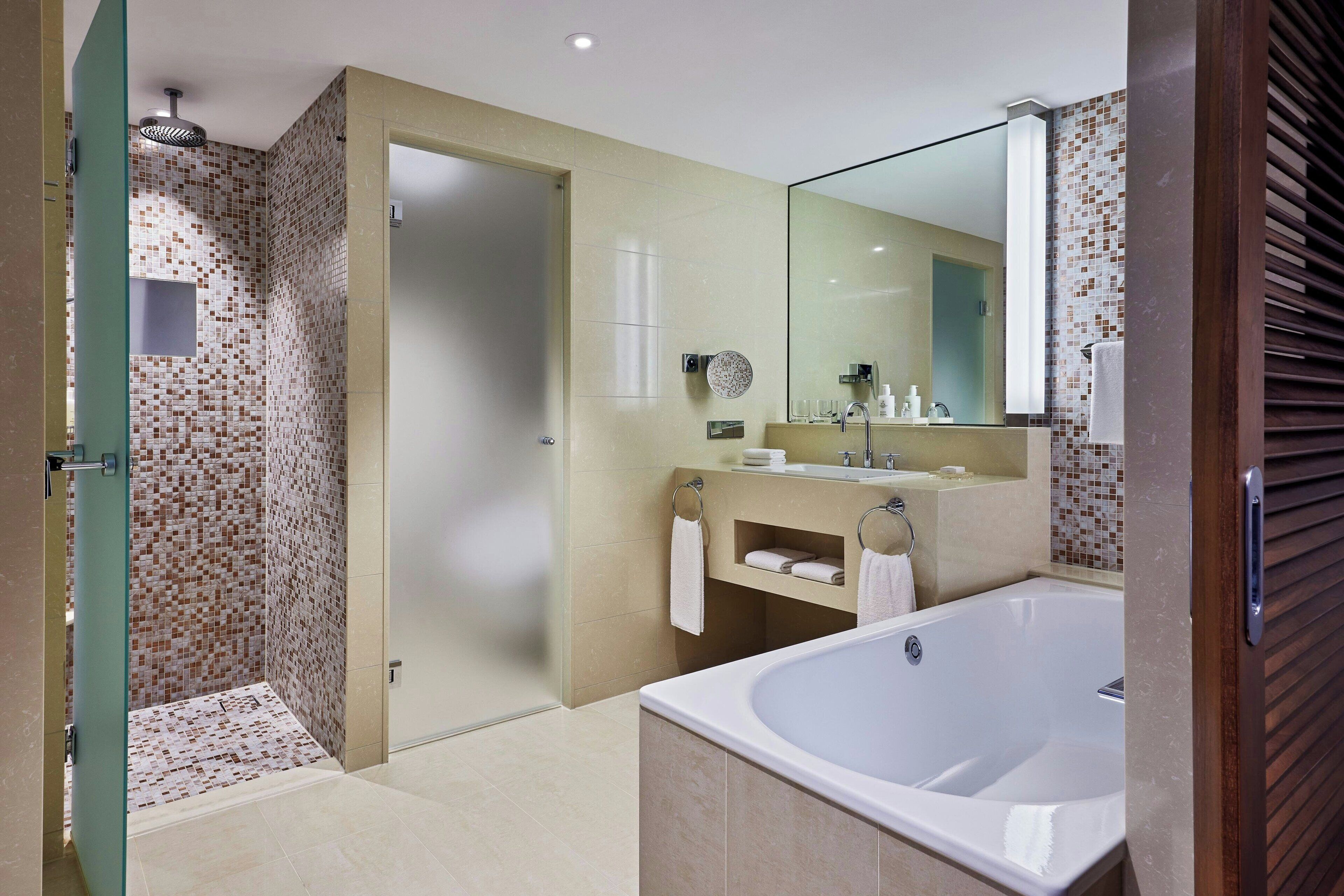 A modern bathroom with a walk-in shower, a large bathtub, and a vanity with a mirror.