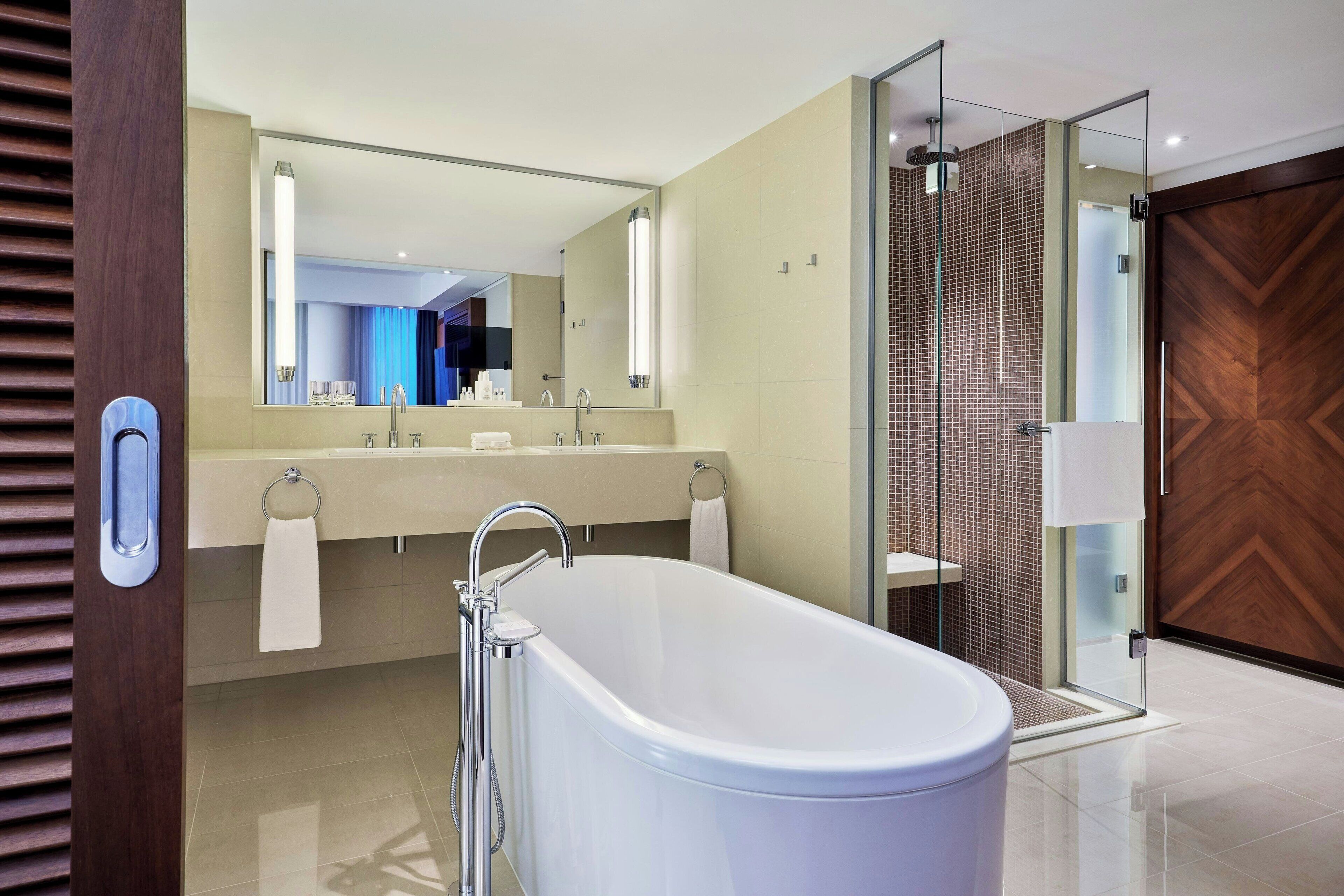 A modern bathroom with a freestanding bathtub, a glass-enclosed shower, and a large mirror above the sink.