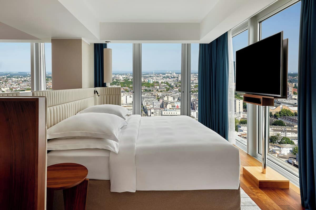 A hotel room with a large bed, a TV, and a city view.