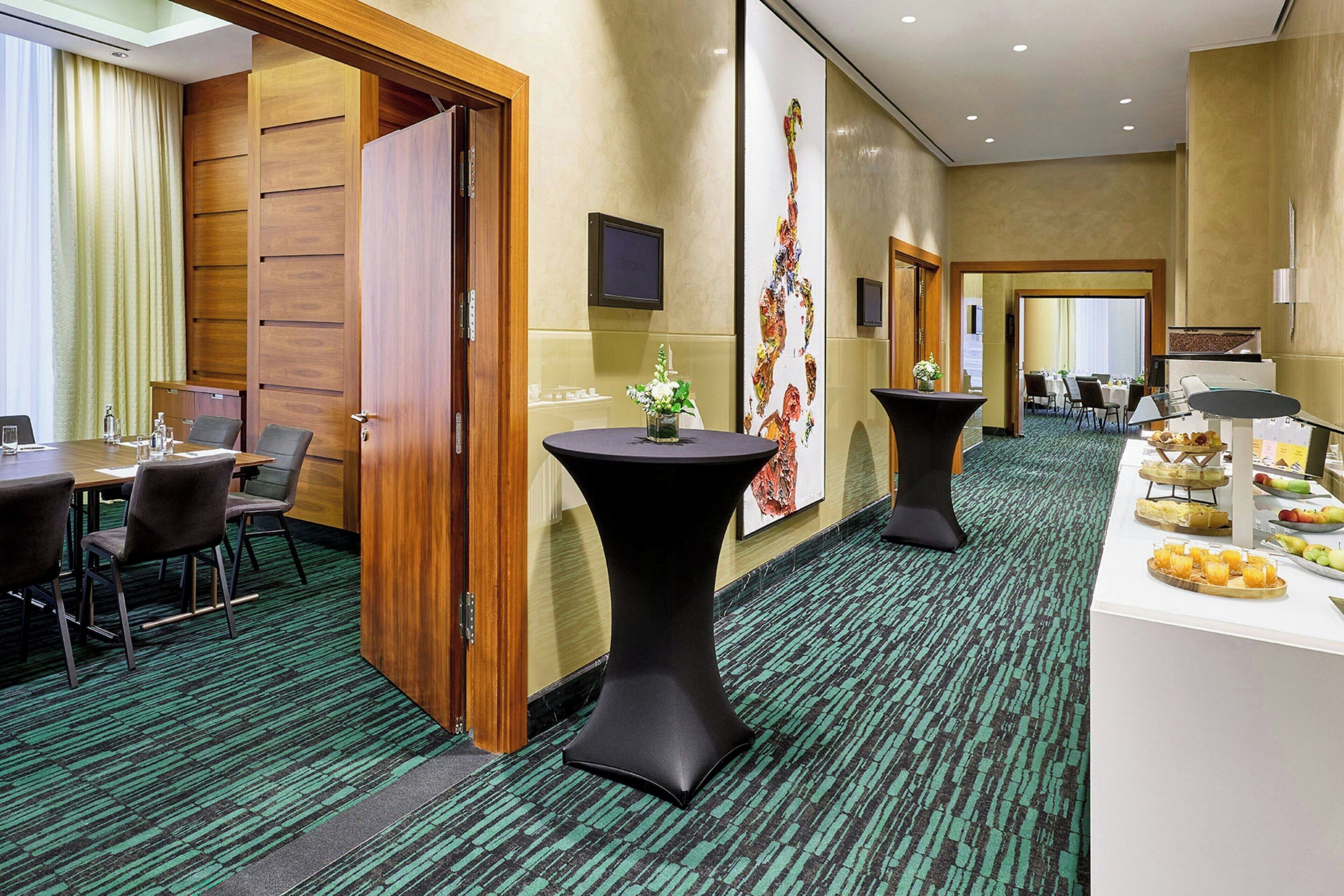 A conference room with a long table, chairs, and a small table with a vase of flowers.