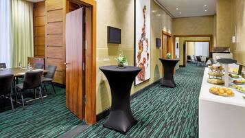 A conference room with a long table, chairs, and a small table with a vase of flowers.