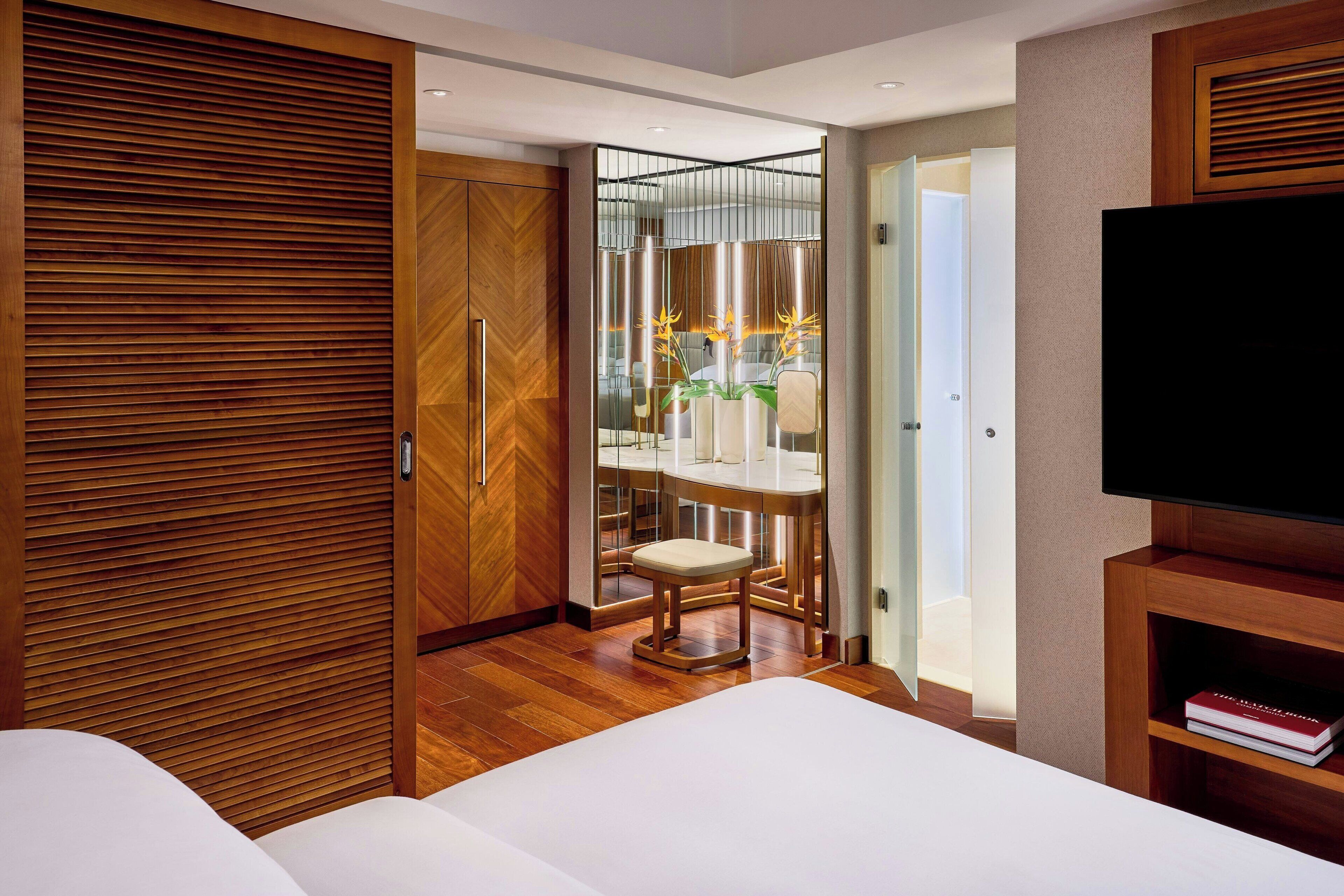 Une chambre d’hôtel avec une armoire en bois, un lit, une télévision et un coin repas comprenant des chaises et une table.