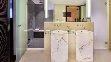 A modern bathroom with two marble sinks, a large mirror, and a glass-enclosed shower area.
