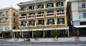 A multi-story hotel with balconies, outdoor seating, and a scooter parked in front.