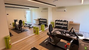 Ett modernt gym med konditionsmaskiner, vikter och en vägg med speglar.