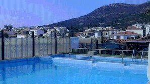 En swimmingpool med utsikt över ett bergigt landskap och bostadshus i bakgrunden.