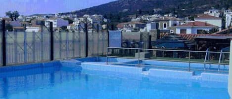A swimming pool with a view of a mountainous landscape and residential buildings in the background.