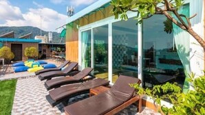 A modern outdoor lounge area with sun loungers and a pool. - Azure Bangla Phuket (Patong)