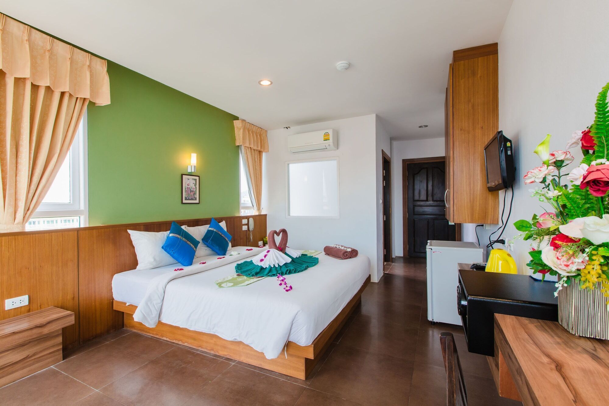 Une chambre d’hôtel avec un lit, un bureau, une télévision et un arrangement floral.