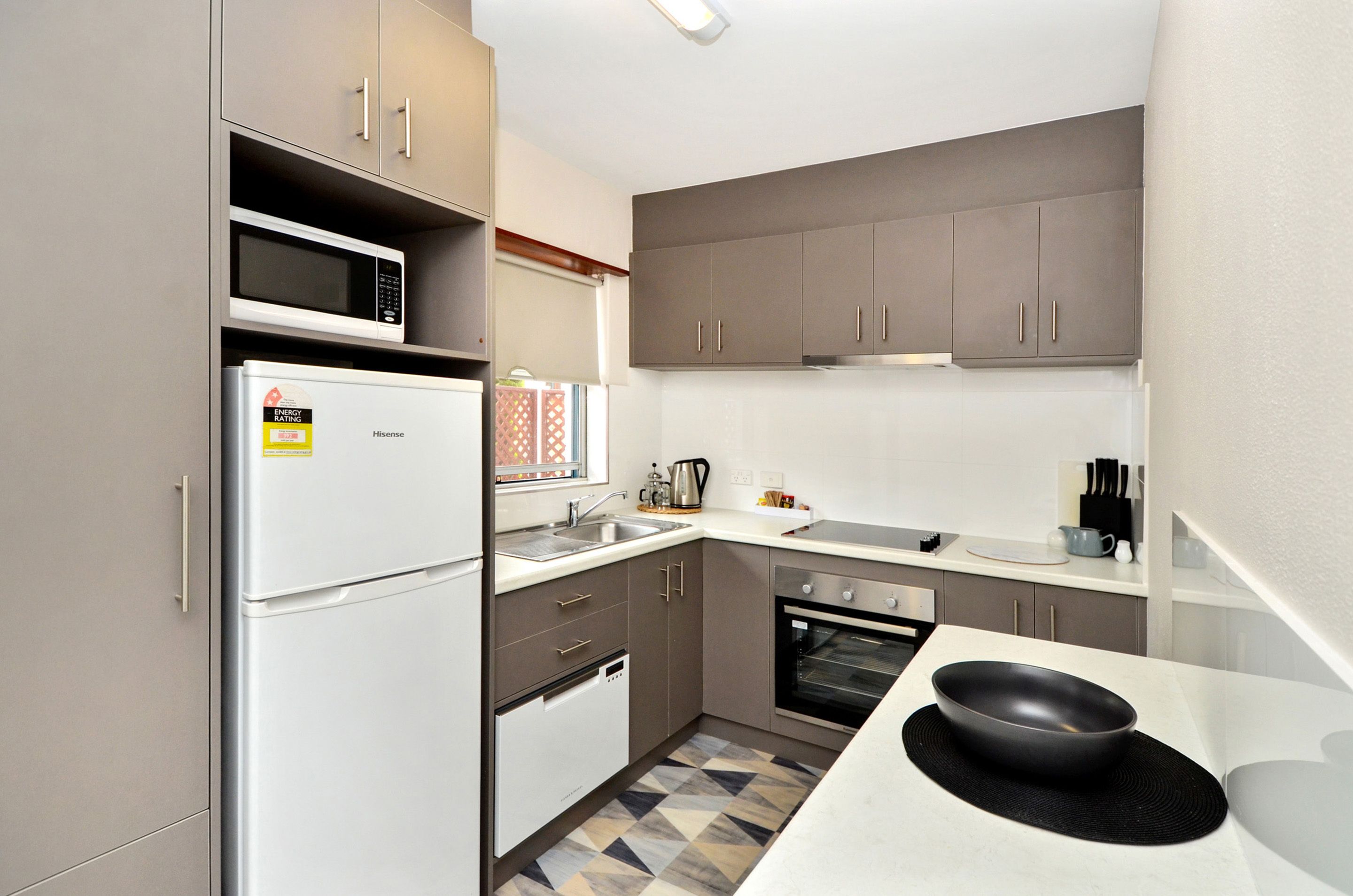 A compact kitchen with a refrigerator, microwave, oven, and sink.